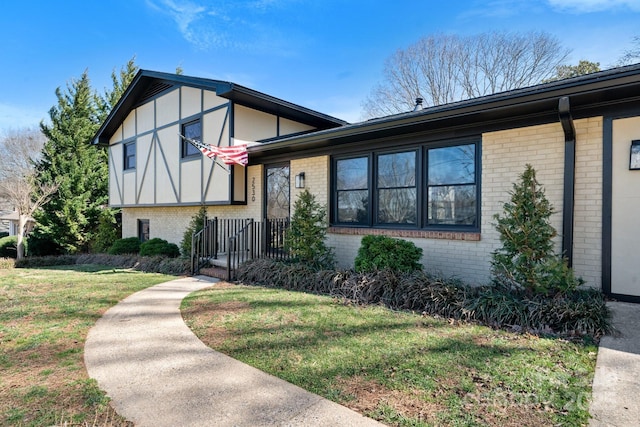 tri-level home with brick siding and a front yard