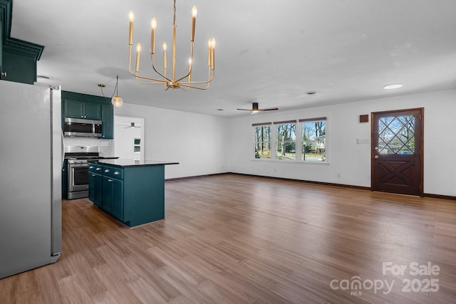 kitchen with dark countertops, appliances with stainless steel finishes, green cabinets, and wood finished floors