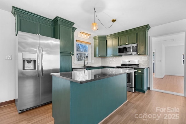 kitchen featuring backsplash, light wood-style floors, appliances with stainless steel finishes, and green cabinetry