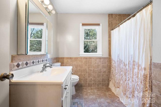 full bathroom featuring a wainscoted wall, toilet, tile walls, and vanity