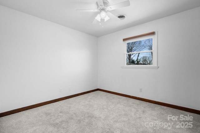 carpeted spare room featuring visible vents, baseboards, and a ceiling fan