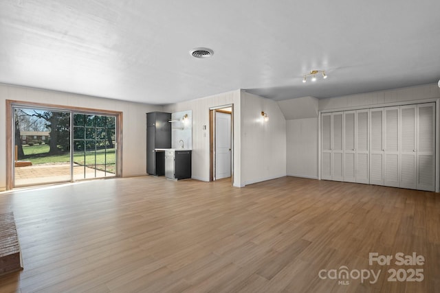 unfurnished living room featuring a sink, visible vents, and light wood finished floors