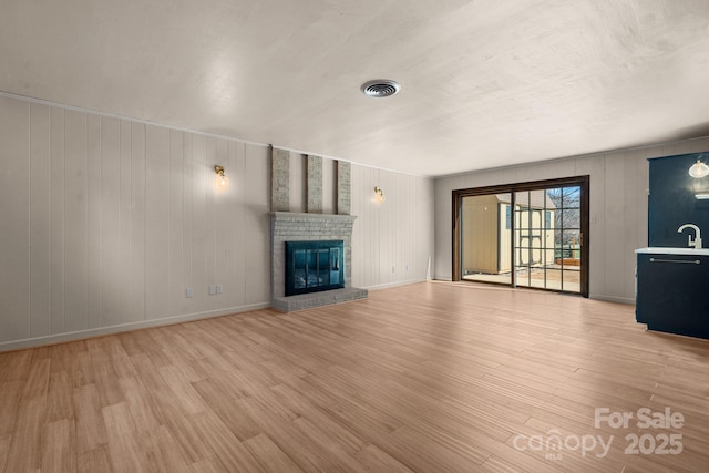 unfurnished living room with visible vents, light wood-style flooring, a fireplace, and baseboards