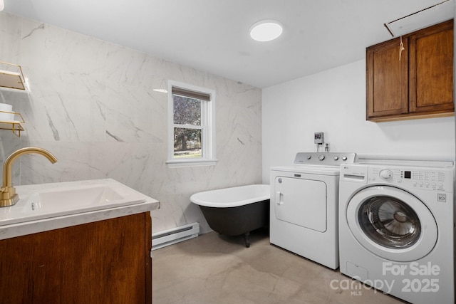 washroom with washing machine and dryer, baseboard heating, cabinet space, tile walls, and a sink