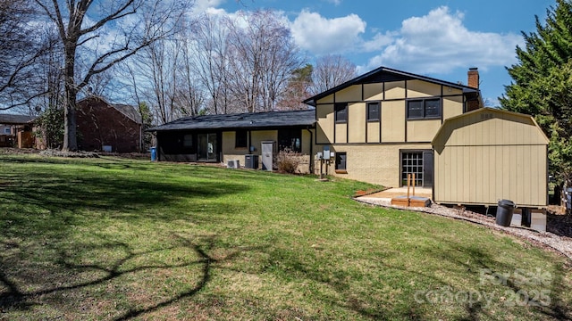 back of property with an outbuilding, a yard, a storage shed, brick siding, and a chimney