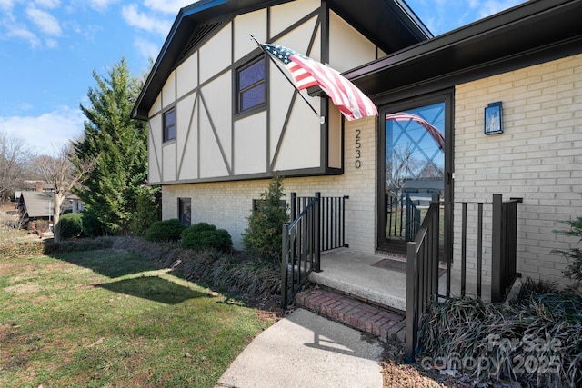 doorway to property featuring a lawn and brick siding