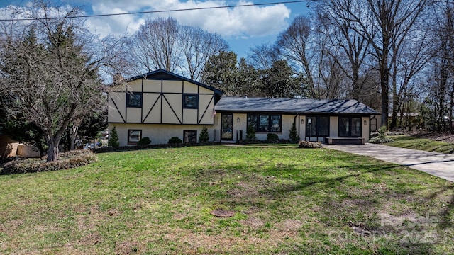 tri-level home featuring a front yard, stucco siding, brick siding, and a chimney