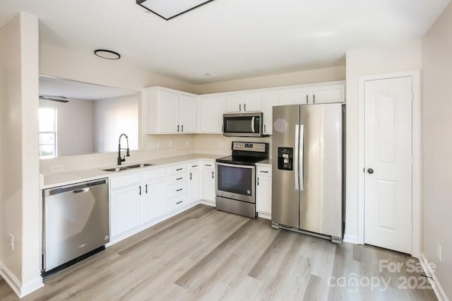 kitchen featuring a sink, light countertops, light wood-style floors, appliances with stainless steel finishes, and white cabinetry