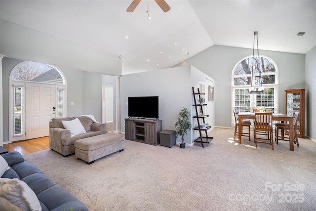 living area featuring high vaulted ceiling, visible vents, a ceiling fan, baseboards, and carpet