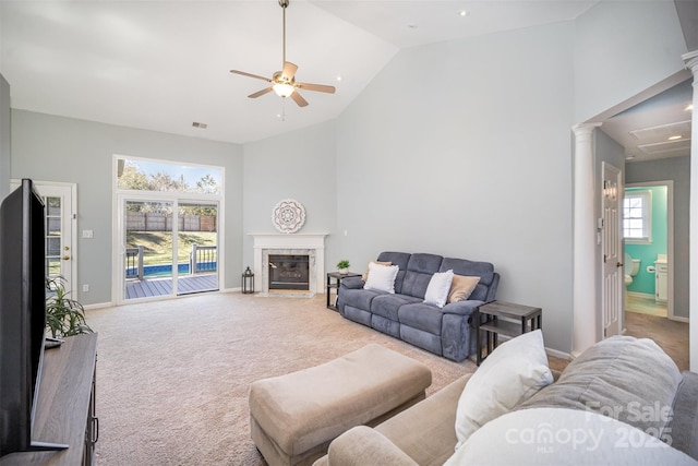 carpeted living area featuring decorative columns, baseboards, visible vents, a premium fireplace, and high vaulted ceiling