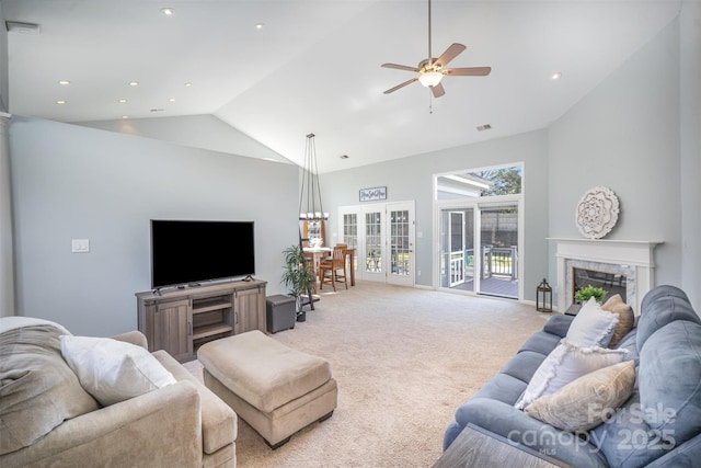 living area featuring light carpet, visible vents, a ceiling fan, a fireplace, and high vaulted ceiling