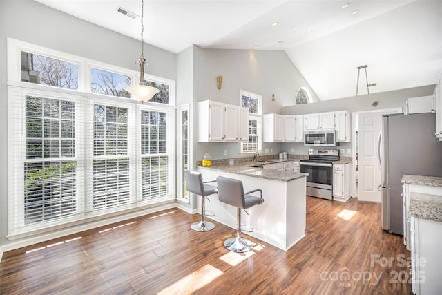 kitchen with stainless steel appliances, a peninsula, a sink, visible vents, and white cabinetry