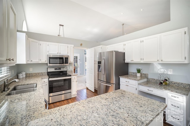 kitchen featuring lofted ceiling, appliances with stainless steel finishes, a sink, and light stone countertops