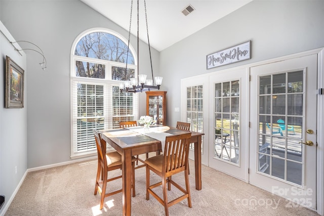 dining space with high vaulted ceiling, a notable chandelier, light carpet, visible vents, and baseboards