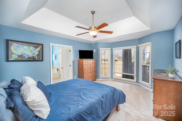 bedroom with ceiling fan, ensuite bath, a raised ceiling, and carpet flooring