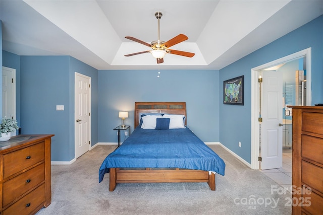 bedroom featuring a raised ceiling, light colored carpet, ceiling fan, and baseboards