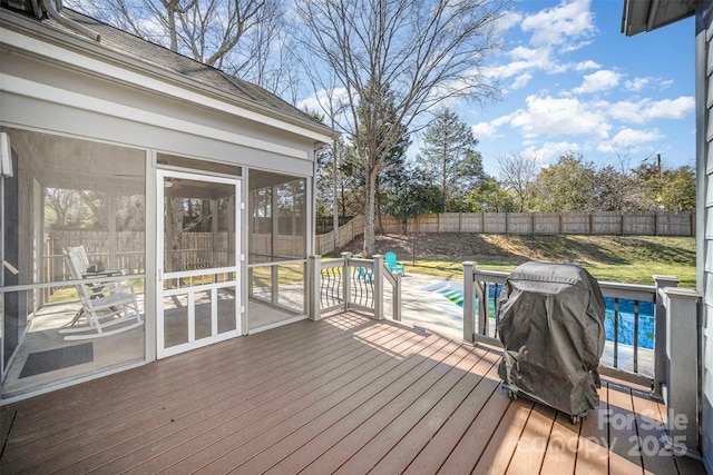 wooden deck with grilling area, a fenced backyard, a sunroom, and a fenced in pool