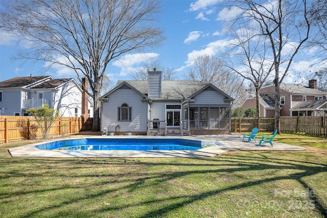 rear view of house featuring a fenced in pool, a sunroom, a fenced backyard, and a yard