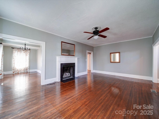 unfurnished living room featuring ceiling fan with notable chandelier, a brick fireplace, baseboards, and wood finished floors