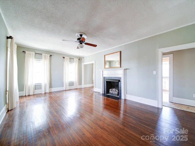 unfurnished living room featuring a fireplace, a ceiling fan, baseboards, ornamental molding, and wood-type flooring