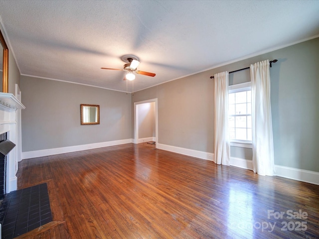 unfurnished living room featuring a fireplace, wood finished floors, a ceiling fan, baseboards, and ornamental molding