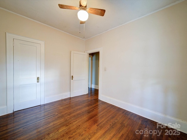 spare room with dark wood-style floors, ornamental molding, a ceiling fan, and baseboards