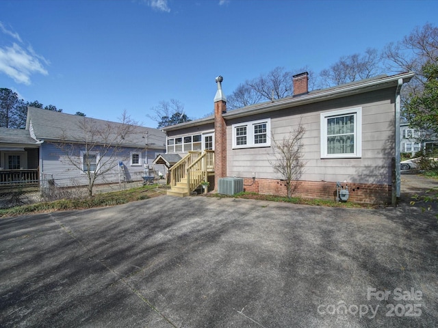 view of front of house featuring a chimney and central AC unit