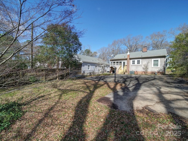 back of house with fence and a chimney