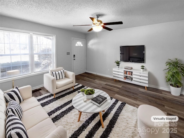 living area featuring ceiling fan, wood finished floors, baseboards, and a textured ceiling