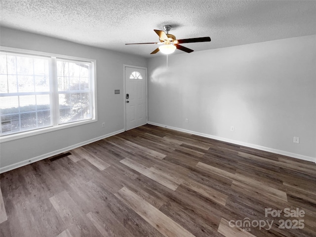 interior space with dark wood-style floors, ceiling fan, baseboards, and a textured ceiling