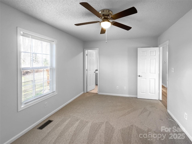 unfurnished bedroom featuring carpet, baseboards, visible vents, and a textured ceiling