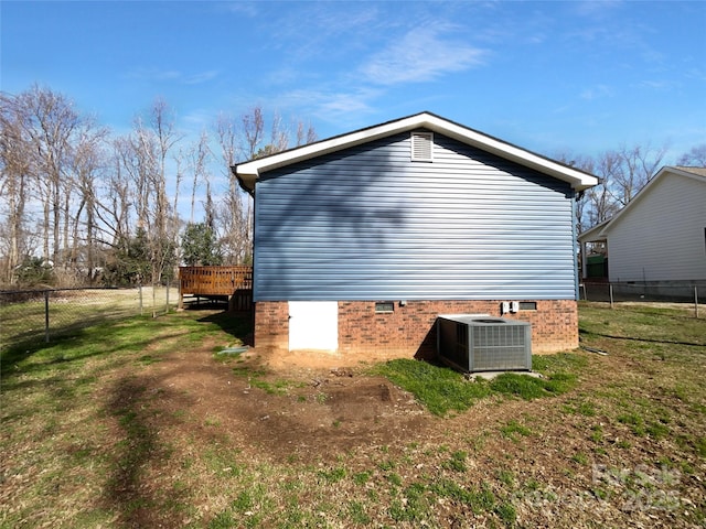 view of side of property featuring a lawn, crawl space, fence, a deck, and cooling unit