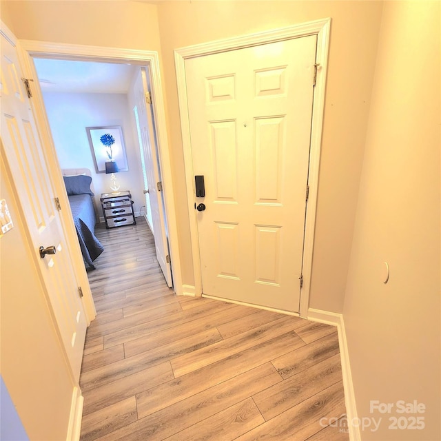 corridor featuring baseboards and light wood finished floors