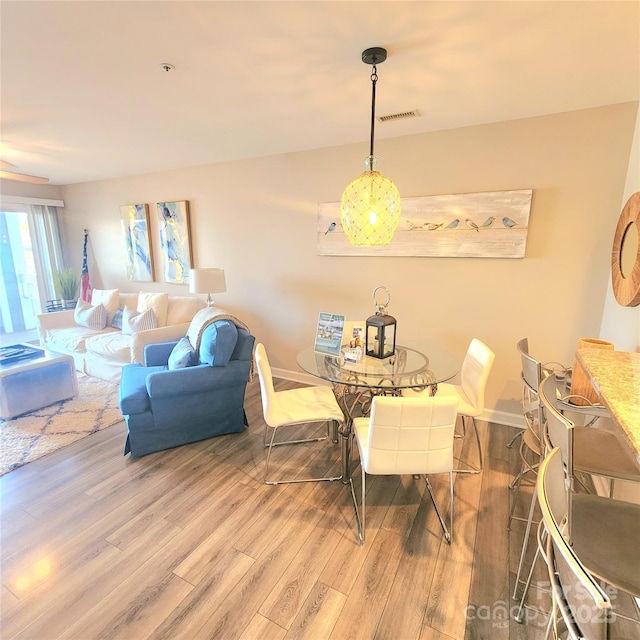 dining space with visible vents, baseboards, and wood finished floors