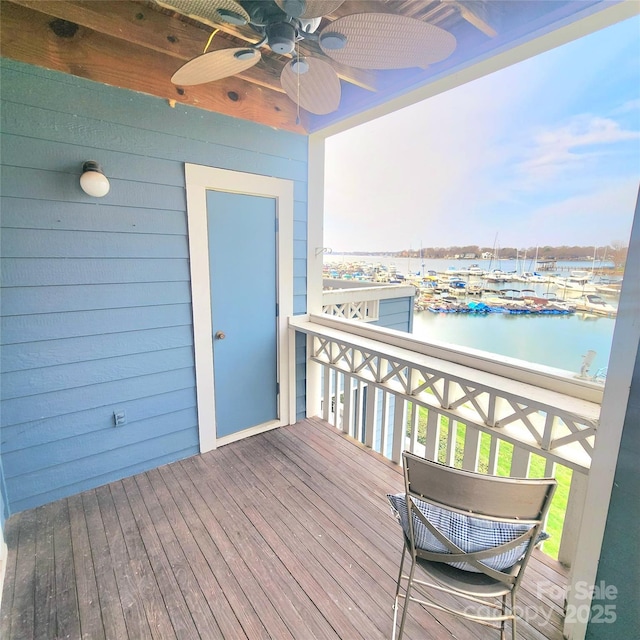 wooden deck with a water view and ceiling fan