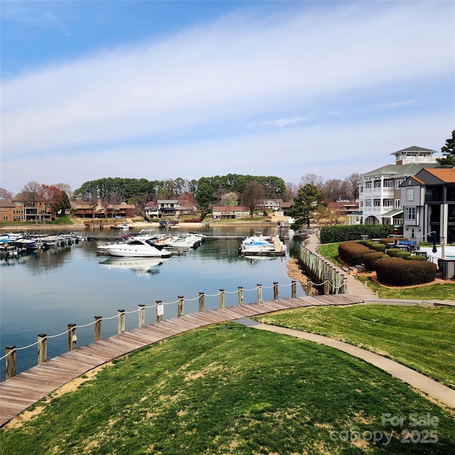 view of dock with a lawn and a water view