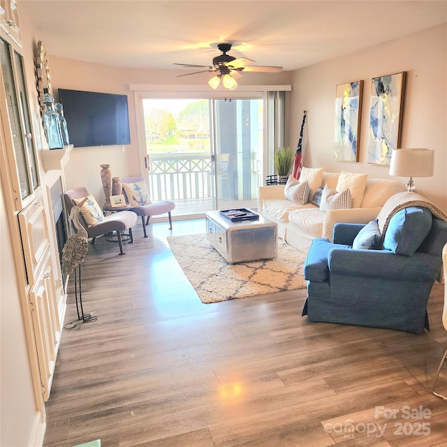 living area with a ceiling fan and wood finished floors