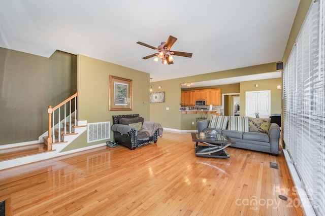 12723 Willingdon Rd, Huntersville, NC 28078 - living area featuring light wood-style flooring, visible vents, baseboards, stairs, and a ceiling fan