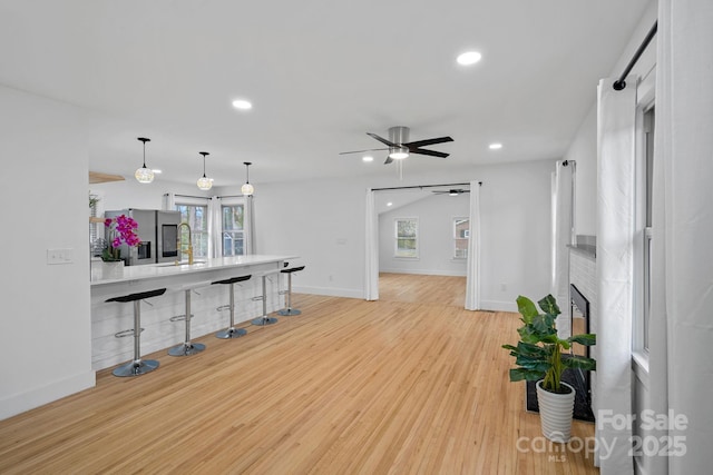 living room with light wood-style flooring, recessed lighting, a fireplace, baseboards, and ceiling fan