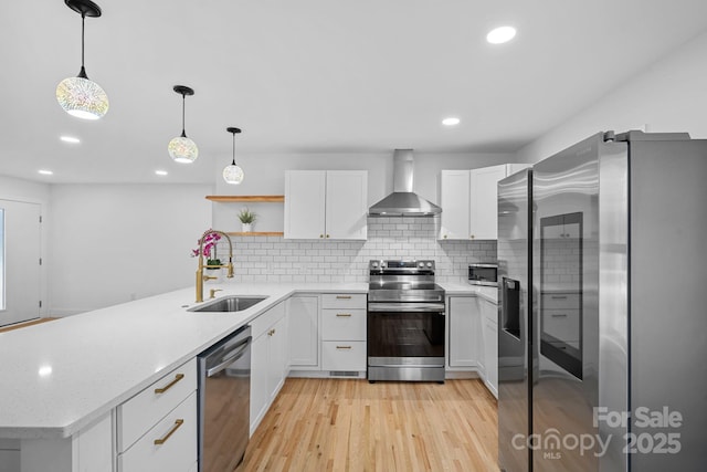 kitchen with a sink, appliances with stainless steel finishes, a peninsula, wall chimney exhaust hood, and open shelves