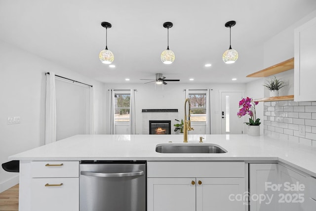 kitchen with a sink, open shelves, stainless steel dishwasher, a peninsula, and a healthy amount of sunlight