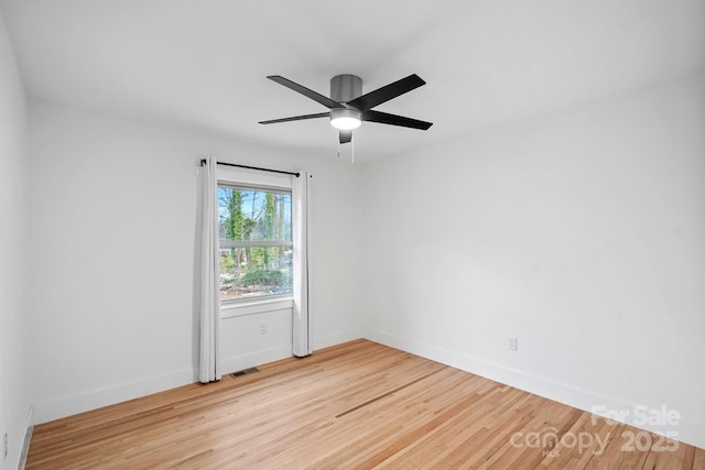 spare room featuring visible vents, ceiling fan, baseboards, and wood finished floors