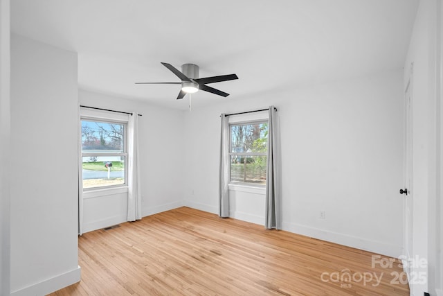 spare room with light wood-type flooring, baseboards, visible vents, and a ceiling fan