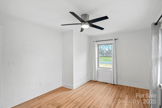 empty room featuring ceiling fan, baseboards, and wood finished floors