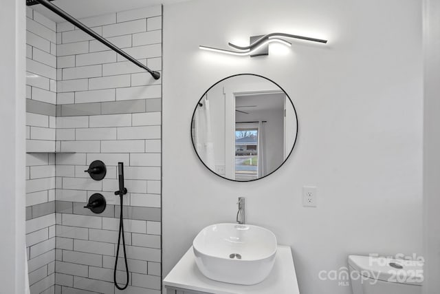 full bathroom featuring vanity, toilet, and tiled shower