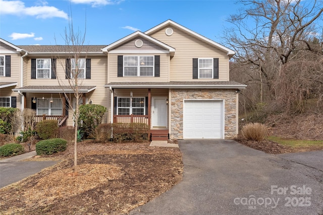 view of front of home with a porch, a shingled roof, a garage, stone siding, and aphalt driveway