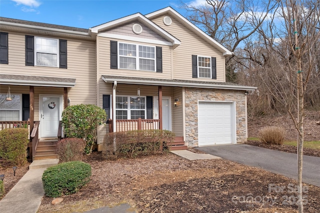 view of front of property featuring stone siding, an attached garage, covered porch, and driveway