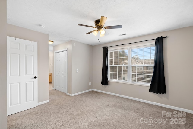 unfurnished bedroom featuring baseboards, visible vents, a closet, a textured ceiling, and carpet flooring