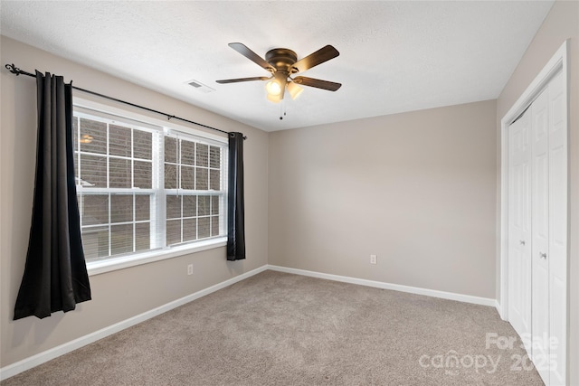 unfurnished bedroom featuring visible vents, a textured ceiling, a closet, carpet flooring, and baseboards