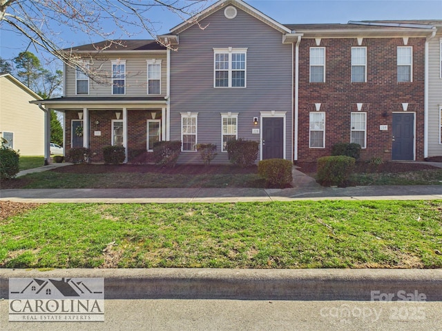 townhome / multi-family property with brick siding and a front yard